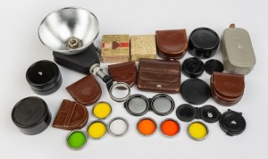 ROLLEI: Twenty-six accessories - seven approx. 38mm diameter lens filters, one Rolleiflash, five lens caps, six small leather cases, two vintage lens filter boxes, four black plastic cases, and one gradient holder in leather pouch. (26 items)