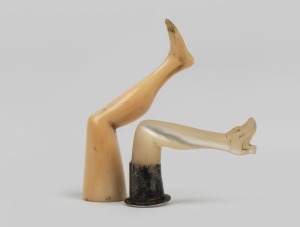 Two novelty pipe tampers in leg form, carved mother of pearl and silver, and a carved ivory example, 19th century, (2 items), the larger 5.5cm high