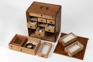 An antique Japanese bonsai gardening box with sliding door revealing a bank of eleven drawers with contents, Meiji Period/Taisho Period, 20th century, 25cm high