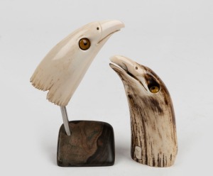 WAYNE BARRETT two carved whale's teeth in the for of eagle heads, both signed "W.B.", 20th century, one with bespoke stand, the larger tooth 12cm long