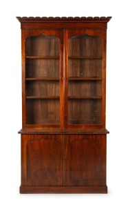 An impressive Colonial Australian cedar two door bookcase with inverted carved tulip centurion style pediment and shield shaped doors, Tasmanian origin, circa 1840, 250cm high, 135cm wide, 46cm deep