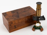 19th-century brass and steel microscope with orange and green painted base, 17 cm at highest setting,&nbsp;in timber box.