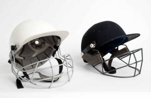 BEN HOLLIOAKE'S BATTING HELMETS, one in navy blue made by Masuri; other white made by Albion, both with grills.