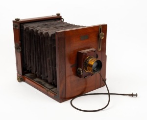 Half-plate tailboard camera with Taylor, Taylor & Hobson Series III Cooke 6½ x 4¾" lens [#6854], roller-blind shutter, shutter release cable, and 'Baker & Rouse' retailer's inlay.