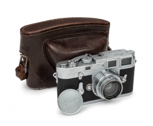 LEITZ: Leica M3 rangefinder camera [#952 529], c. 1959, with Summar 50mm f2 lens [#316606]. Later iteration with single-stroke film advance mechanism. Metal lens cap and brown leather case with strap also present.