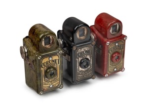 CORONET: Three c. 1935 Midget subminiature Bakelite cameras - one in red, one in dark green, and one in black. (3 cameras)