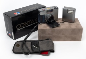 YASHICA: Contax T rangefinder camera [#030581], c. 1984, in silver with Carl Zeiss Sonnar T 38mm f2.8 lens. Offered in maker's box with Contax T14 Auto flash accessory, suede case, wrist strap, and printed materials.