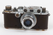 LEITZ: Chrome Model F Leica III [#139050 - corresponding to 1934], with Elmar 50mm f3.5 lens and with brown leather Leica case. Defaced Reichsadler&nbsp;symbol and anomalous 'M 66' engravings&nbsp;present above serial number on top plate likely to be fanciful addit - 2