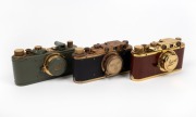LEITZ (COUNTERFEIT): Three attractive but fanciful counterfeit 'Leicas', likely modified FED or Zorki models, each with 'Leitz Elmar' 50mm f3.5 lens and&nbsp;lens cap - one&nbsp;in gold and polished timber, one in gold and teal with fascist engraving on viewfinder,