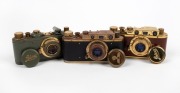 LEITZ (COUNTERFEIT): Three attractive but fanciful counterfeit 'Leicas', likely modified FED or Zorki models, each with 'Leitz Elmar' 50mm f3.5 lens and&nbsp;lens cap - one&nbsp;in gold and polished timber, one in gold and teal with fascist engraving on viewfinder, - 2