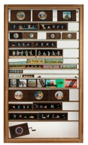 70 x 122.5cm wooden framework containing containing thirty-nine glass slides representative of the history of image projection, including magic lantern slide sequences of various sizes, a chromatrope, Val Morgan cinema advertisement slides, and others.