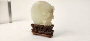 An antique Chinese jade ornament carved with blossom tree, on carved timber stand, Qing Dynasty, 18th/19th century, 8cm high overall - 8