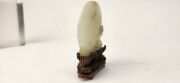 An antique Chinese jade ornament carved with blossom tree, on carved timber stand, Qing Dynasty, 18th/19th century, 8cm high overall - 11