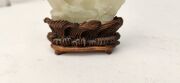 An antique Chinese jade ornament carved with blossom tree, on carved timber stand, Qing Dynasty, 18th/19th century, 8cm high overall - 12