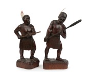 A pair of carved timber Maori warrior statues with feather decoration, 20th century, one signed to base "Hoko Pai", the larger 35cm high