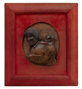 A fine antique New Zealand carved and polished kauri gum relief plaque depicting a Maori woman with chin moko carrying a child, circa 1880s, housed in original red velvet frame (worn), and bearing paper label verso "Thomas's Picture Frame Manufactory, Sydney Road Brunswick", 21 x 18cm, 40 x 36cm overall