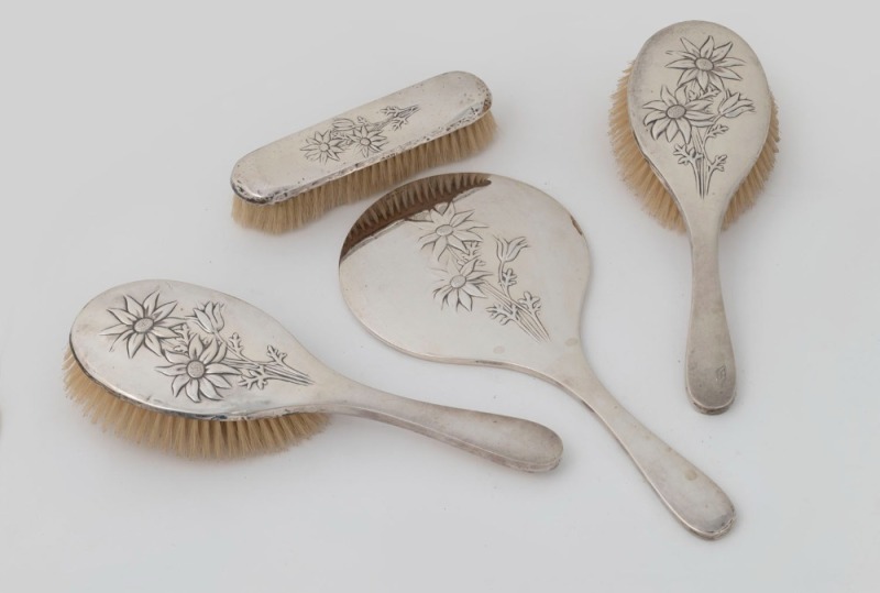 An antique English sterling silver four piece brush and mirror set with Australian flannel flower repousse decoration, by Deakin & Francis, Birmingham, 1910, the mirror 32cm high