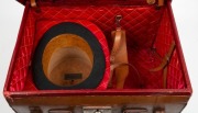 An antique top hat in original red silk lined leather travel case, 19th century, the hat bearing label "D. BUZOLICH, 'THE HAT SPECIALIST', RAILWAY BUILDINGS, FLINDERS & SWANSTON STS.", ​​​​​​​the case 48cm wide - 2
