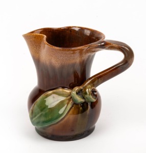 REMUED brown and green glazed pottery jug with applied gumnuts, leaf and branch handle, incised "Remued, 118M", 11cm high