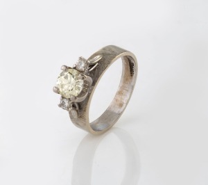 An 18ct platinum ring, set with an impressive brilliant cut champagne diamond flanked by a pair of brilliant cut white diamonds, 20th century, stamped "18. PLAT", 4.7 grams