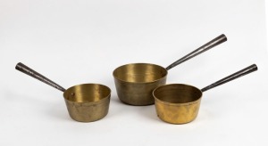 An antique graduated set of three heavy gauge brass saucepans with iron handles, 19th century, the largest 44cm long