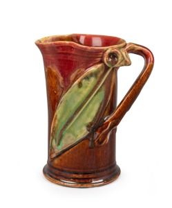 REMUED pink and brown glazed pottery vase with early green glazed leaf highlights adorned with applied gumnuts, leaf and branch handle, incised "Remued, Hand Made 172/5M", 13.5cm high