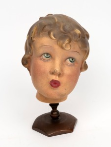 An antique shop display mannequin child's head, painted plaster on metal stand, early 20th century, 26cm high