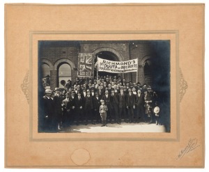 A circa January 1916 silver gelatin photograph (13.5 x 19cm), laid down on backing card (W. Mason & Co. of Bridge Road, Richmond), depicting a group of men in front of the recruiting office under a banner which reads "RICHMOND'S 1st QUOTA of RECRUITS For Australia's New Army of 50,000". The men are photographed with their recruiting officers and a young, uniformed mascot. Overall 24 x 29cm. In January 1916, the Army announced that it needed 50,00 men for the "New Army", and 16,000 reinforcement