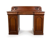 An antique Australian Colonial cedar twin pedestal sideboard in the classical manner, with recessed arch panels to the pedestals, crossbanded inserts, inverted break front top with three cushion moulded drawers and low back with scroll carving Athenian de