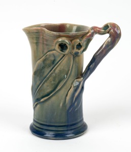 REMUED pottery jug with applied gumnuts, leaf and branch handle, unusual blue, mauve and pink glaze, incised "Remued, Hand Made", 17cm high