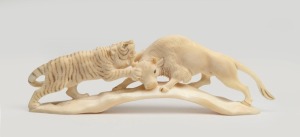 A Japanese carved hippopotamus tooth depicting a tiger attacking a buffalo, 20th century, ​​​​​​​16cm long