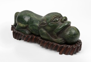 A carved Chinese jade mythical creature on carved wooden stand, 20th century, an impressive 16cm high, 38cm long overall