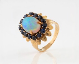 A vintage 14ct yellow gold cocktail ring, set with a solid cabochon opal surrounded by Australian blue sapphires, stamped "14K", 7.3 grams total