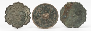 Three assorted antique Chinese bronze mirrors, two lotus shaped and the other a circular example with remains of silver and gold inlay, the largest 16cm wide