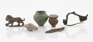 Six assorted bronze and copper Roman artefacts, including fibula brooches, arrowhead, merchant weights and sword pommel, the largest 6cm long