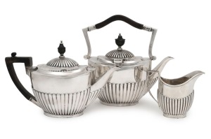 An antique English sterling silver three piece tea service by Goldsmiths & Silversmiths Company of London, circa 1904, the largest piece 22cm high, 1300 grams total including wooden handles1500