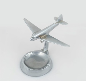 Trench Art: Douglas DC3 mounted on ashtray, c. 1940s, solid chrome-plated brass, 14cm high and 20cm wingtip to wingtip.