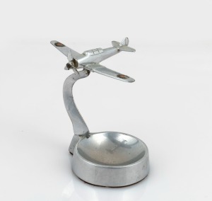 Trench Art: CAC Wirraway&nbsp;mounted on ashtray, c. 1940s, solid chrome-plated brass, 9.5cm high and 9cm wingtip to wingtip.