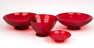 WHITEFRIARS&nbsp;four English ruby red glass footed bowls with ribbon trail decoration,&nbsp;mid 20th century, one example with remains of blue foil export label, the largest 28cm high