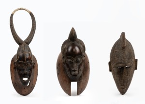 Three assorted tribal masks, carved wood and fibre with remains of painted finish, African origin, the largest 52cm high