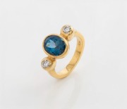 An 18ct gold ring, set with blue sapphire flanked by two brilliant cut white diamonds, stamped "750", 9.2 grams