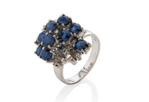 A vintage 18ct white gold designer cocktail ring, adorned with blue sapphires and white diamonds, stamped "18ct", 8.2 grams total