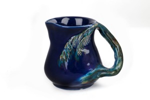 CRUFFEL blue and green glazed porcelain jug with wind swept handle, bearing original foil label "Art Porcelain", 12cm high, 15cm wide