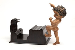 A vintage bakelite kookaburra cigarette dispenser; together with a Brownie Downing porcelain figural plaque, 20th century, (2 items), the cigarette dispenser 19cm wide