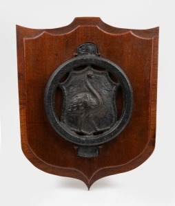An antique cast iron emu rondel mounted on cedar shield panel, 19th century, 39cm high