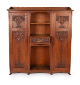 An Australian Arts & Crafts bookcase with knee hole desk compartment, manufactured in American oak, carved with Illawarra flame tree motif, early 20th century, with original ink stamp to the reverse of drawer "MISS GETHERS, WOOD CARVING STUDIO, SYDNEY", 1