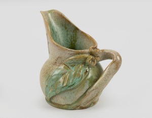 REMUED green glaze pottery jug with applied gumnuts, leaf and branch handle, incised "Remued", with remains of original foil label, 11cm high