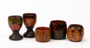 MADGE FREEMAN hand-painted huon pine miniature vase, signed "Madge Freeman, 1924"; together with a pair of huon pine pokerwork floral egg cups and two pokerwork napkin rings, circa 1920s, (5 items), the largest 7cm high