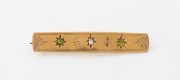 An antique 18ct yellow gold brooch, set with a central diamond flanked by two green sapphires, 19th century, stamped "18ct", ​​​​​​​5.7cm wide, 9.7 grams