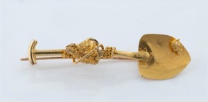 An antique 22ct gold miner's brooch in the form of a shovel and natural gold nugget specimen entwined in rope, 19th century, 4cm long, 2.9 grams